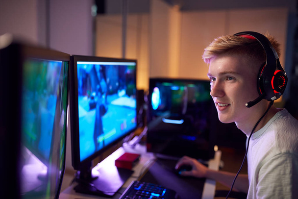 Teenage Boy Wearing Headset Gaming At Home Using Dual Computer Screens - Foto, Imagen