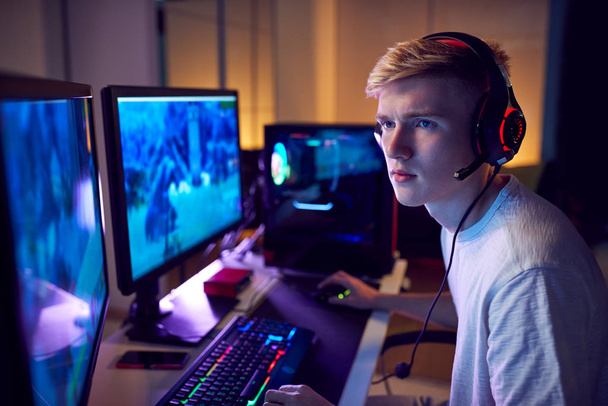 Teenage Boy Wearing Headset Gaming At Home Using Dual Computer Screens - Photo, image