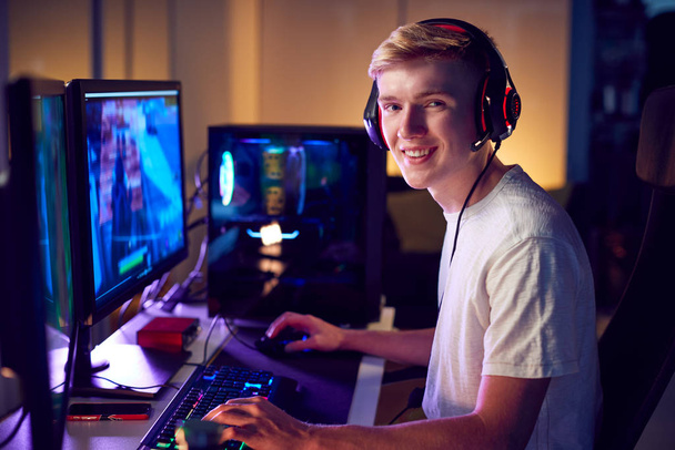 Portrait Of Teenage Boy Wearing Headset Gaming At Home Using Dual Computer Screens - Valokuva, kuva