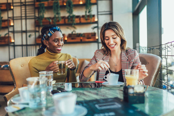 Two female friends talking at a coffee shop - Fotoğraf, Görsel