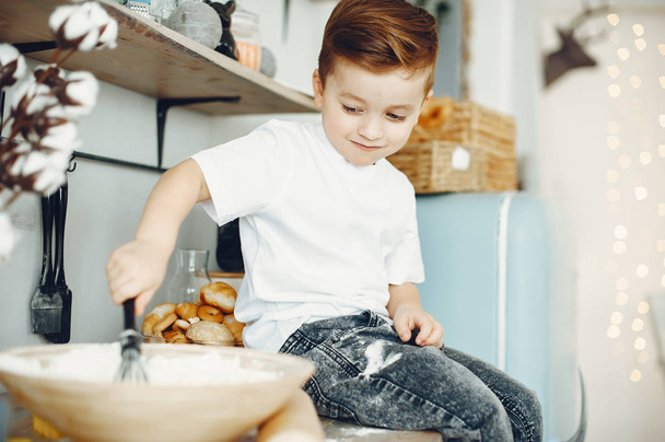 Cute little boy sitting in a kitchen - Фото, изображение