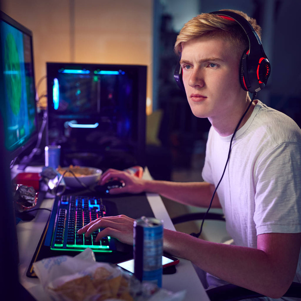 Teenage Boy Wearing Headset Gaming At Home Using Dual Computer Screens - Foto, Bild