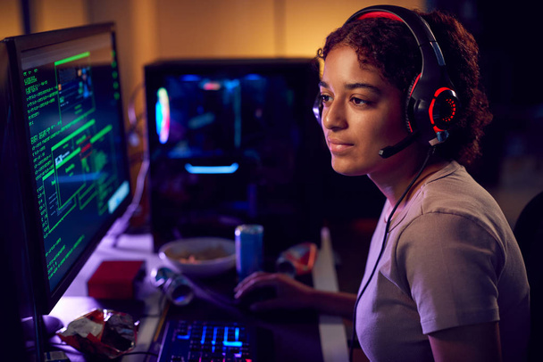 Female Teenage Hacker Sitting In Front Of Computer Screens Bypassing Cyber Security - 写真・画像