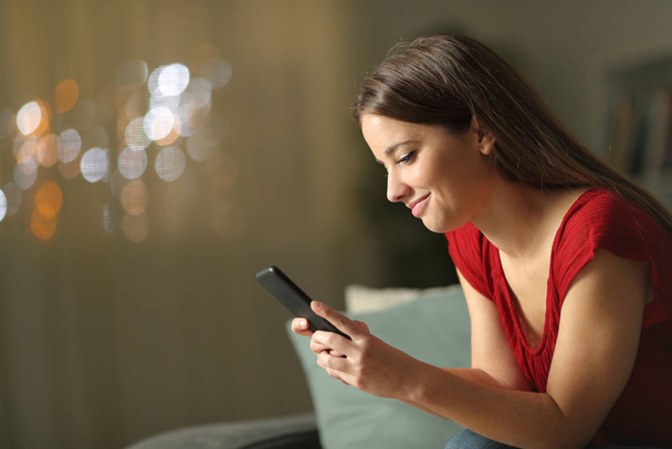 Profil kobiety korzystającej w nocy z telefonu komórkowego w domu - Zdjęcie, obraz