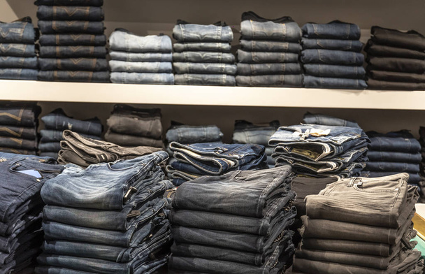 Pilha de jeans dobrados nas prateleiras da loja
 - Foto, Imagem