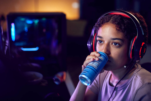 Teenage Girl Drinking Caffeine Energy Drink Gaming At Home Using Dual Computer Screens At Night - Fotó, kép