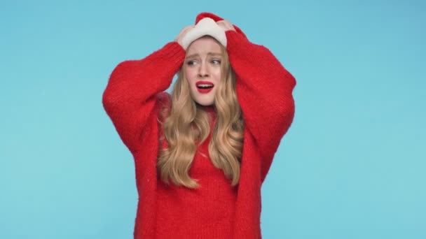 Displeased pretty woman in christmas hat becoming angry and screaming over turquoise background - Footage, Video