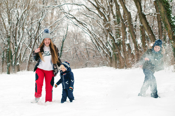 Mamá y sus hijos juegan con nieve en un parque. Hora de invierno. Vacaciones familiares de invierno
. - Foto, Imagen