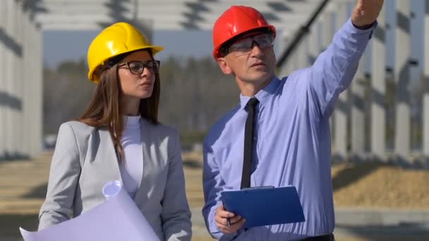 Muž a žena v klobouku Diskutují o projektu Data na staveništi. Starší podnikatel a žena Architekt Plánování stavební projekt na místě - Záběry, video