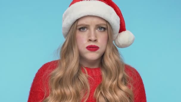 Close up view of Displeased pretty woman in christmas hat becoming angry and screaming over turquoise background - Footage, Video