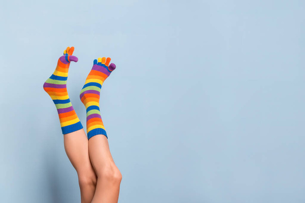  Funny playful woman legs wearing colorful socks over blue background - Fotografie, Obrázek
