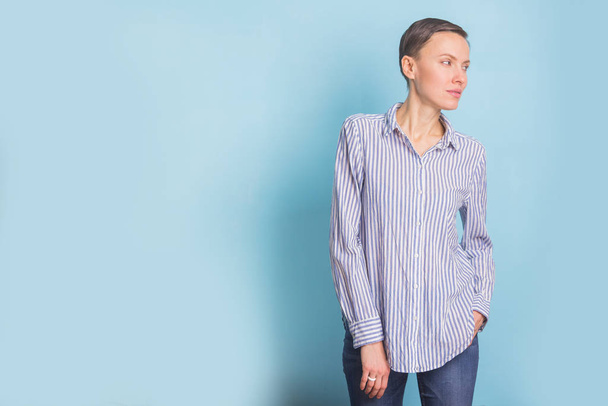 Portrait of a smart and beautiful young woman over light blue background wearing casual shirt and jeans - Zdjęcie, obraz