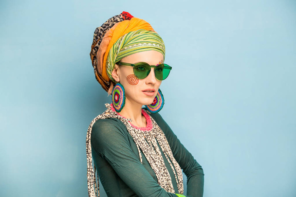 Hermosa mujer con un turbante en la cabeza, pendientes de moda y una pulsera. Concepto de mujer estilo África
 - Foto, imagen