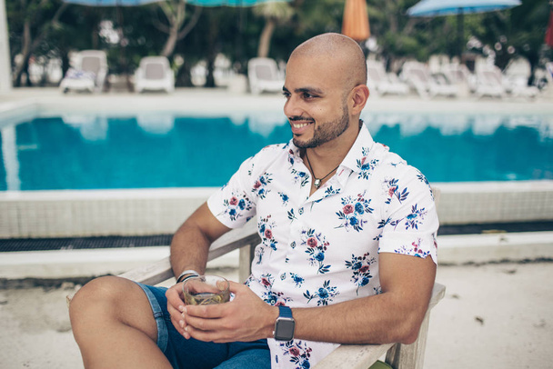 Sporty handsome man with glass of wiskey chilling on the Maldives resort - Fotó, kép
