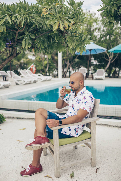 Sporty handsome man with glass of wiskey chilling on the Maldives resort - Zdjęcie, obraz