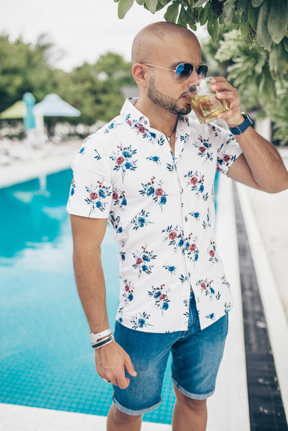 Sportowy przystojny mężczyzna ze szklanką wiskey chilling na Malediwach resort - Zdjęcie, obraz