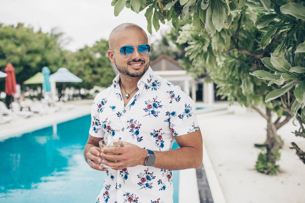 Αθλητικός όμορφος άντρας με ένα ποτήρι κρασί στο θέρετρο Μαλδίβες. - Φωτογραφία, εικόνα
