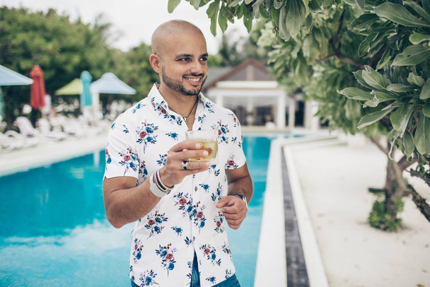 Sporty handsome man with glass of wiskey chilling on the Maldives resort - Photo, image