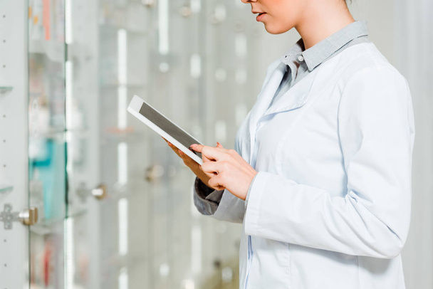 Обрізаний вид жіночого фармацевта з використанням цифрового планшета в аптеці
 - Фото, зображення