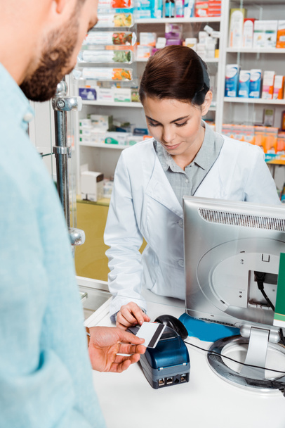 Selective focus of customer with credit card using paypass in pharmacy - Fotografie, Obrázek
