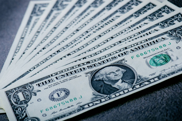 Ein-Dollar-Scheine auf einem schwarzen Tisch. Bares Geld, amerikanische Dollar. Vintage-Hintergrund. Linsenschlag. Amerikanische Währung. - Foto, Bild