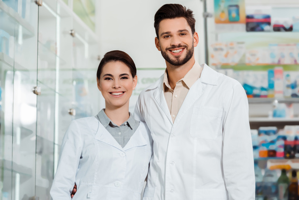Apteekkarit valkoisissa takeissa hymyilevät kameralle apteekissa
 - Valokuva, kuva
