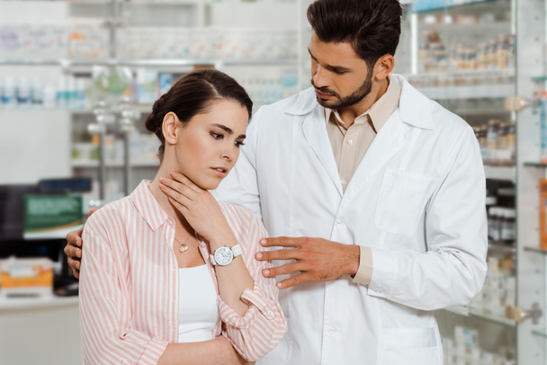Pharmacist beside woman with throat pain in apothecary - Photo, Image