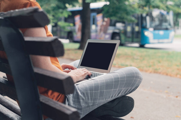 Woman using laptop computer on street bench, mock up screen - Foto, Bild