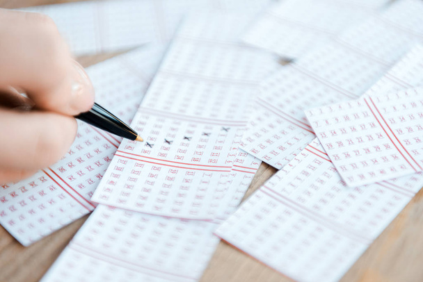 foco seletivo da mulher marcando números em bilhetes de loteria na mesa
 - Foto, Imagem