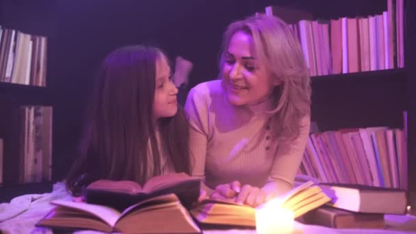Мама і дочка сидять разом і читають казку, кольоровий дим кружляє навколо - Кадри, відео