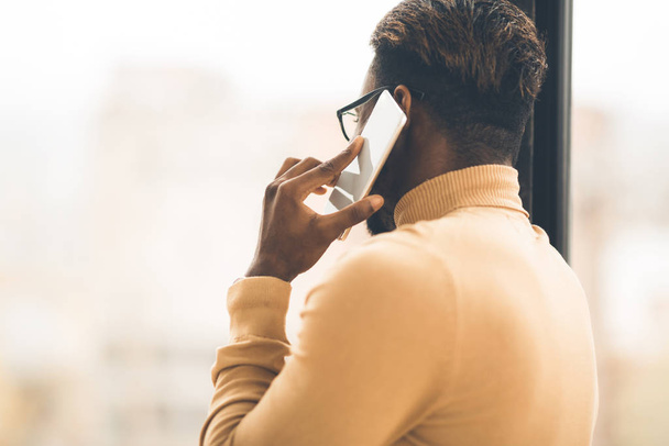 Nierozpoznawalny czarny mężczyzna rozmawiający przez telefon - Zdjęcie, obraz