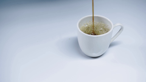 hot espresso pouring into cup on white  - Filmati, video