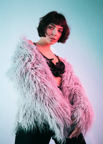 Young girl in a pink fur coat blue background studio red light  - Photo, Image