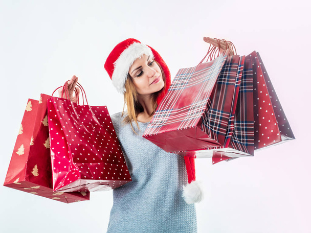 Young pretty woman in santa hat holding christmas bags - Zdjęcie, obraz