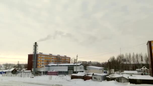 Winter cityscape in siberian city. Smoke is falling from pipe. Truck is driving along road. Day. Surgut, Russia - December 17, 2019. - Video