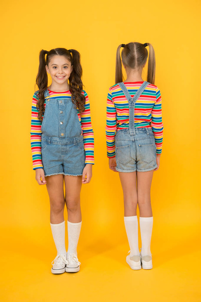 Stylish and confident. compare little girls yellow background. hairdresser salon. kid summer fashion. beauty and style. childhood life. happy school friendship. best friends. small sisters have fun - Фото, изображение