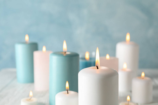 Different burning candles against blue background, space for tex - Foto, Bild