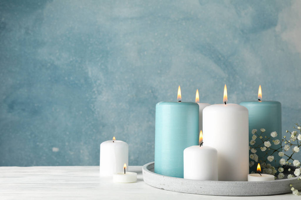 Κάψιμο κεριών, δίσκος και λουλούδι σε μπλε φόντο, χώρος  - Φωτογραφία, εικόνα
