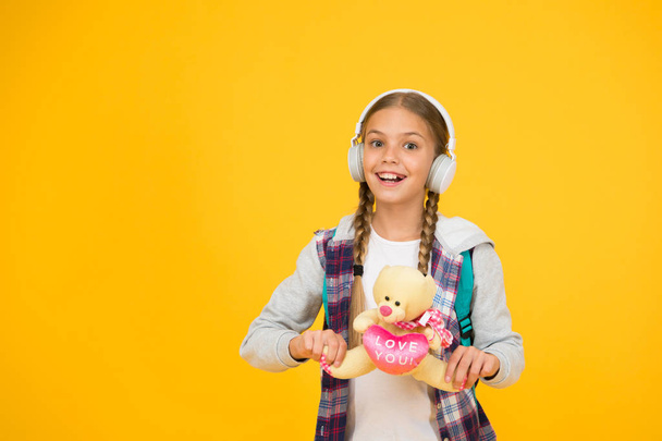 love toys. hipster girl lpove play with toy. schoolgirl casual style hold bear toy. autumn time for knowledge. child listen music headset. childhood education and development. audio book - Valokuva, kuva