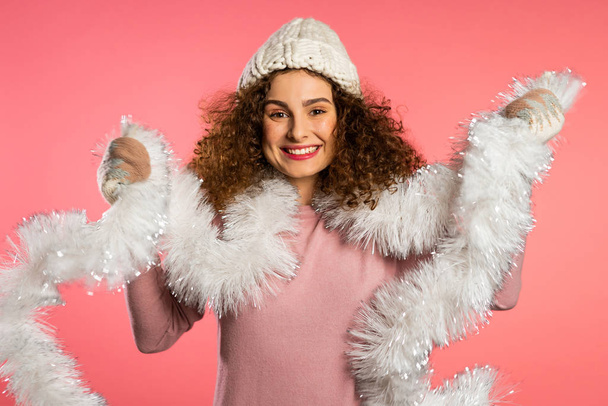 Ritratto di donna in cappello a maglia, guanti e maglione caldo sorridente su sfondo rosa studio. Ragazza in buon umore di Natale invernale
. - Foto, immagini