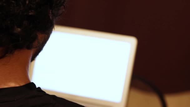 Człowiek pracujący w domu na laptopie z białym ekranem. Widok z tyłu z bliska. Przestrzeń kopiowania - Materiał filmowy, wideo