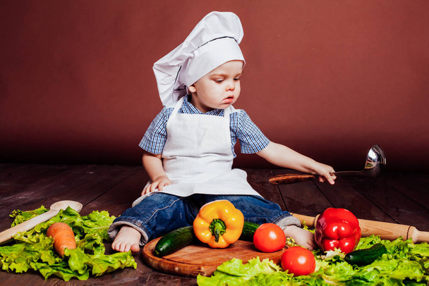 kis fiú Cook sárgarépa, paprika, paradicsom, fejes saláta, - Fotó, kép