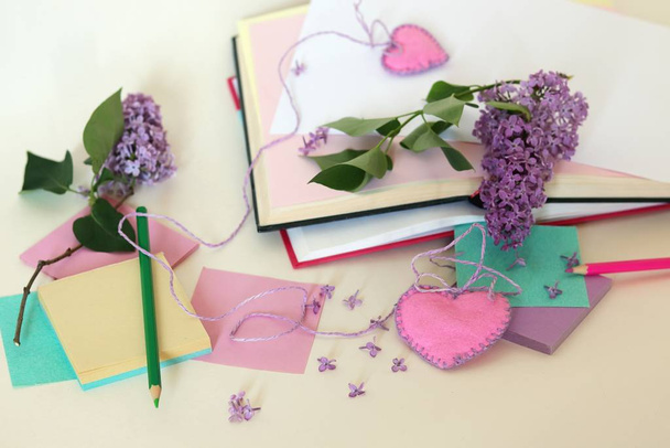 Větve fialových květin na stole, papír, zápisníky, tužky, příprava pozdravů na Valentýna - Fotografie, Obrázek