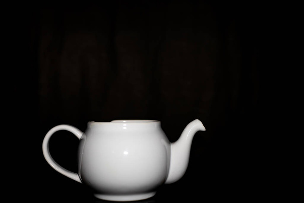 Photo of a white ceramic kettle with shadows from light and a bl - 写真・画像