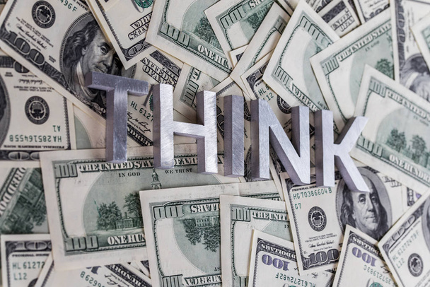 The word THINK laid with aluminium letters on the US dollar banknotes background - with selective focus - Photo, Image