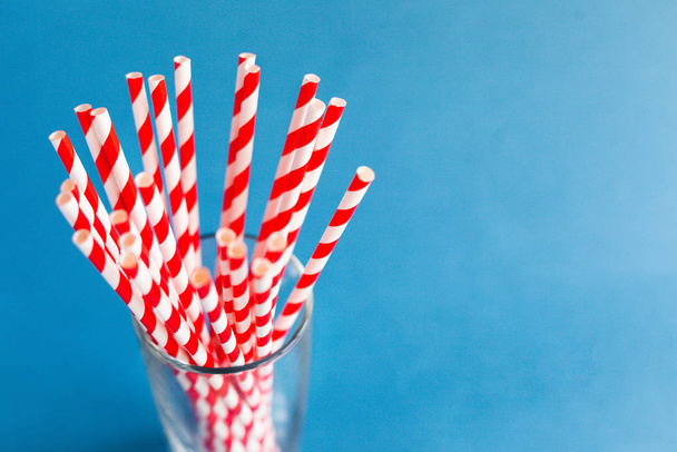 Red cocktail straws in a glass on a blue background - Fotografie, Obrázek