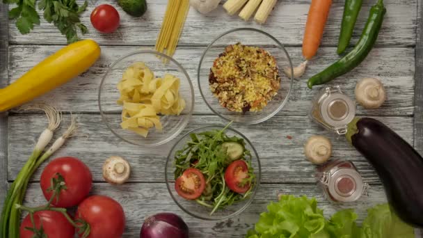 Erntehelfer heben 3 Schüsseln mit Lebensmitteln auf dem Tisch unter gesunden Zutaten ab - Filmmaterial, Video