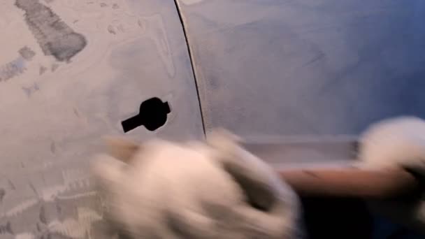 Detailní záběr mužských rukou v rukavicích s brusným nástrojem. Broušení dveří auta poškozených po nehodě. Příprava kovového povrchu pro nanášení a lakování. - Záběry, video