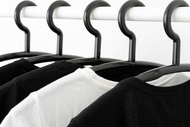vêtements de couleur noir et blanc sur cintres dans la garde-robe
 - Photo, image
