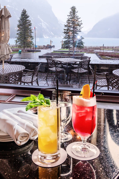 Coloridos cócteles tropicales no alcohólicos en la mesa del restaurante Banff Springs Hotel con fondo Chateau Lake Louise
. - Foto, imagen